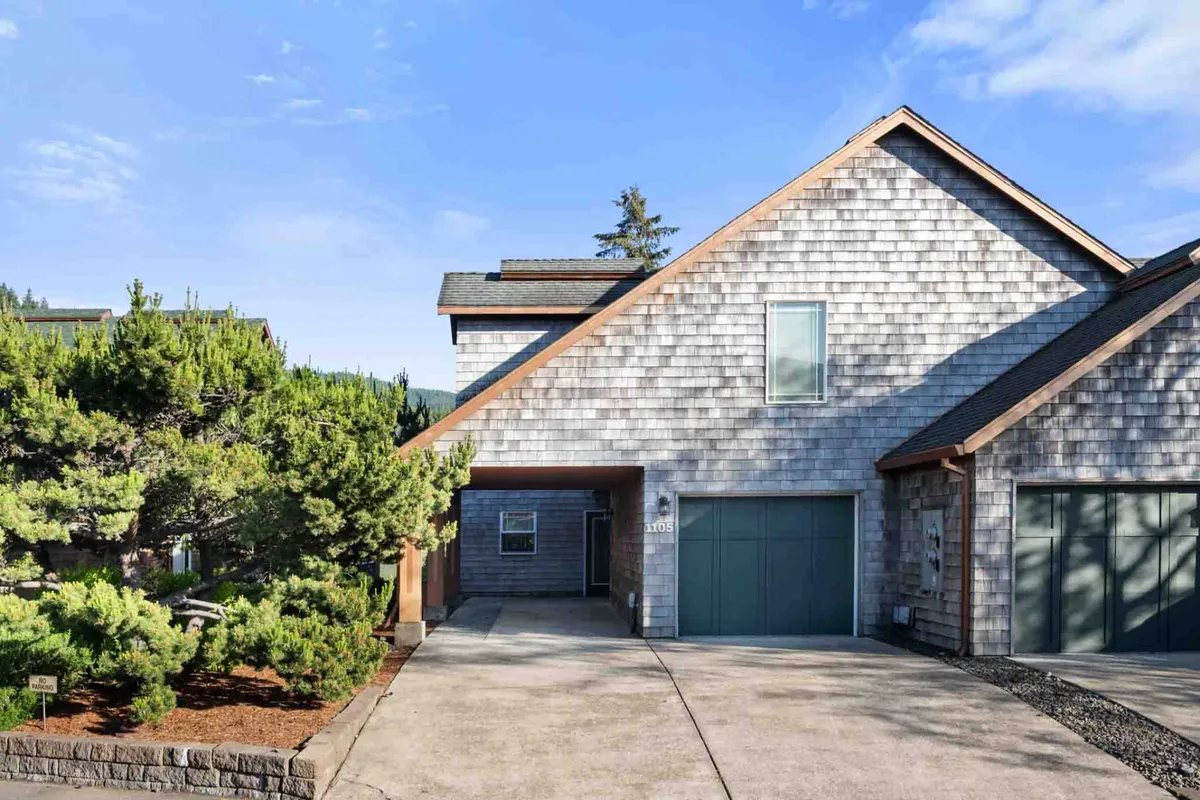 The image displays the home's exterior with wooden shingles, a garage door, and a landscaped front yard, evoking a sense of arrival and connection to the surrounding neighborhood. The setting suggests opportunities for outdoor gatherings and friendly interactions, enhanced by the welcoming curb appeal.
