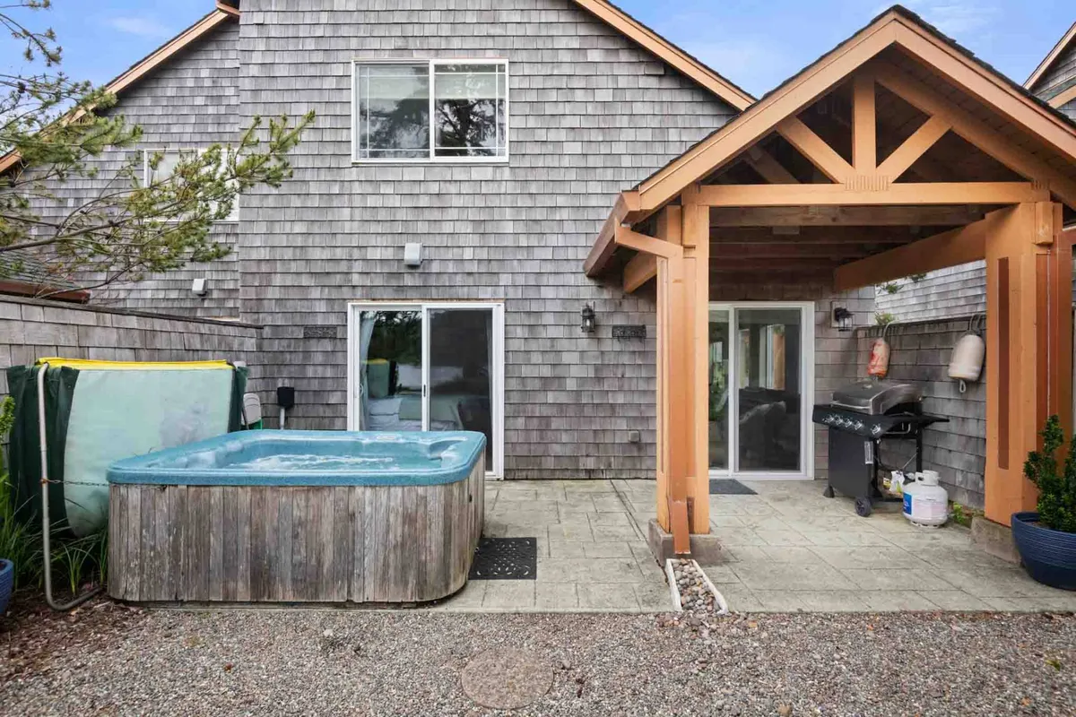 This exterior shot features a hot tub and outdoor grill on a spacious patio area. The arrangement suggests a welcoming environment for alfresco dining, socializing, and soaking with lake views in the background.