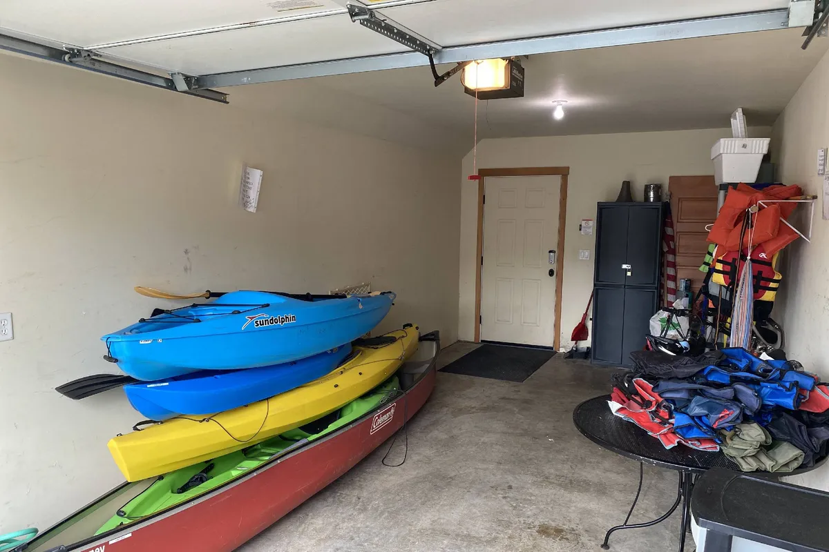 The image features a set of colorful kayaks and life jackets arranged near a table with outdoor gear, suggesting an active, adventure-ready environment. The space has an inviting, open feel, likely adjacent to the outdoors, and evokes the spirit of exploration and play.