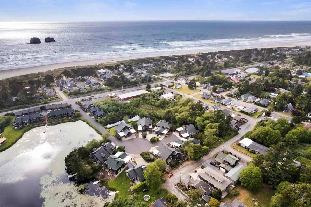 A sweeping view of the ocean coastline with the nearby town layout and a lagoon visible. The image conveys the proximity to community amenities, panoramic ocean views, and the inviting natural environment that frames the beach area.