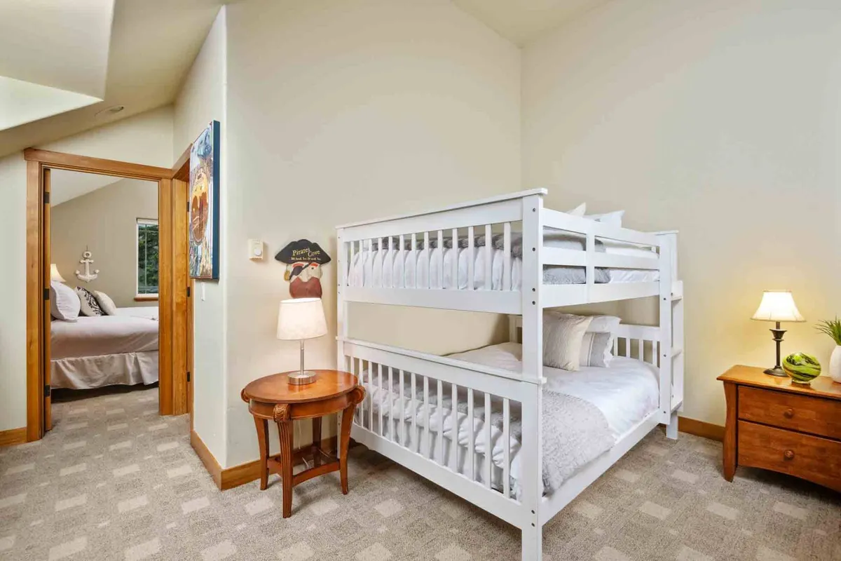 A family-friendly bedroom with a full-size bunk bed, a nightstand with a lamp, and playful artwork. The room radiates coziness and is ideal for children or extra guests, inviting stories and bonding at bedtime.